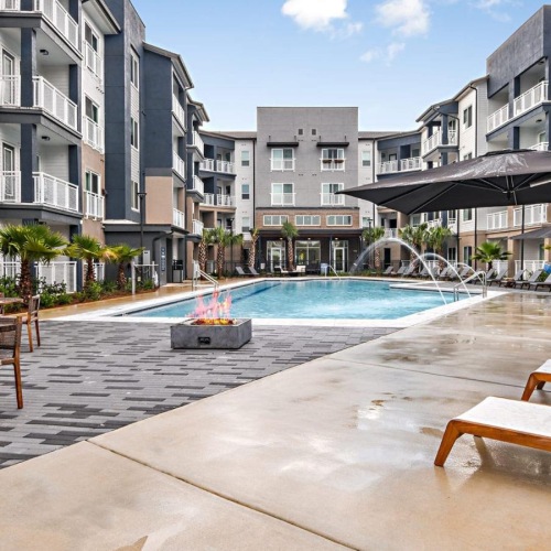 Relax and unwind poolside pool with fountains next to fire pit and lounge chairs