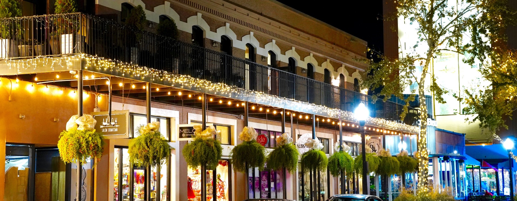 Nighttime view of a cozy, decorated street with storefronts and string lights, similar to the hidden local spots near The 52 Apartments in Pensacola